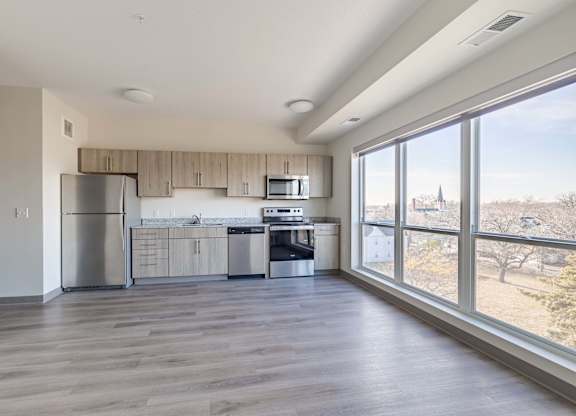 A spacious kitchen with wooden floors and stainless steel appliances.