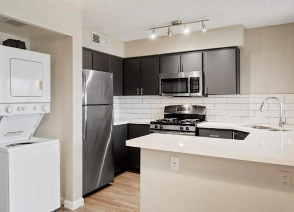 Kitchen with stainless steel appliances and washer and dryer next to it at Sentry Tempe apartments in Tempe near Mesa, Arizona