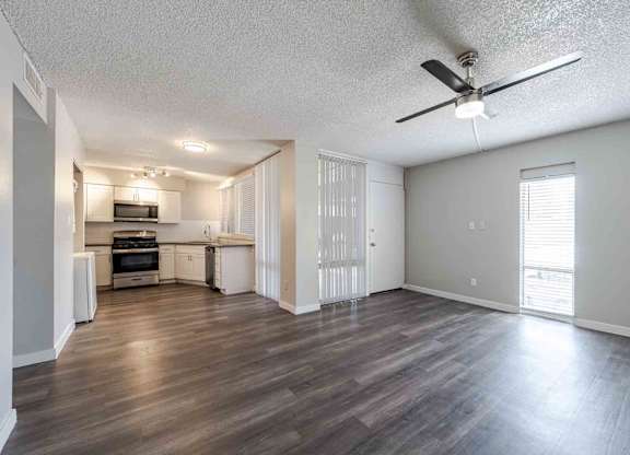 A spacious living room with a kitchen in the background.