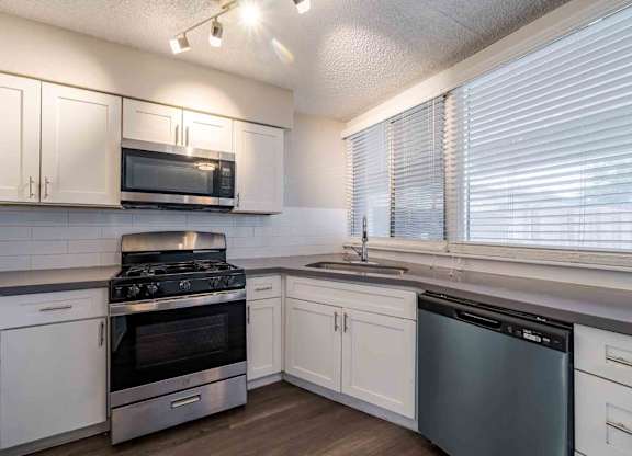 A kitchen with white cabinets and stainless steel appliances.