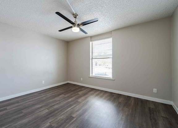 A room with a ceiling fan and a window with blinds.
