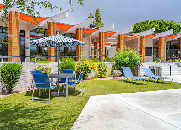 A patio with a table and chairs is in front of a building.