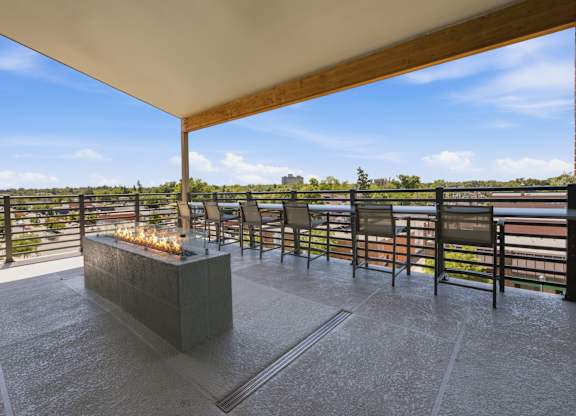 A patio with a fire pit and chairs overlooking a body of water.