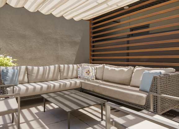 A white couch with blue pillows is on a patio.