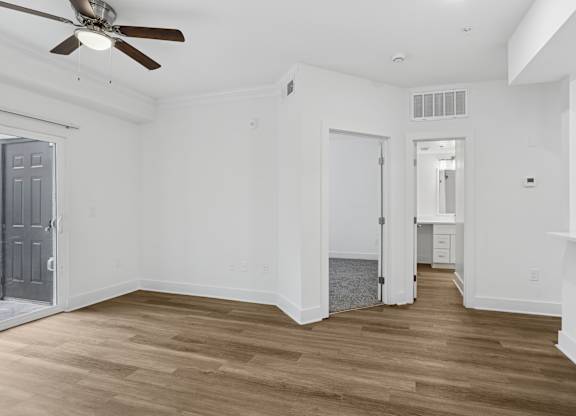 A room with a ceiling fan and wooden flooring.