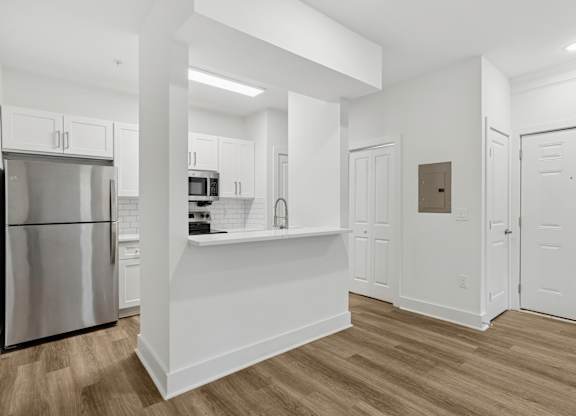 A kitchen with white cabinets and a stainless steel refrigerator.