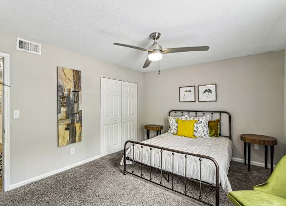 A bedroom with a bed, a chair, and a painting on the wall.