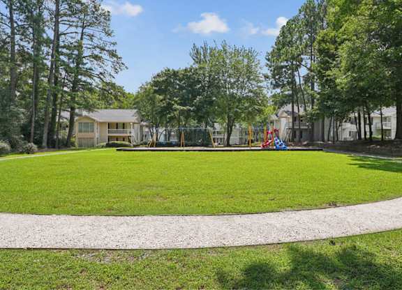 A park with a playground and a house in the background.