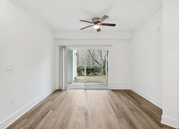 A room with a ceiling fan and sliding glass doors leading to a garden.