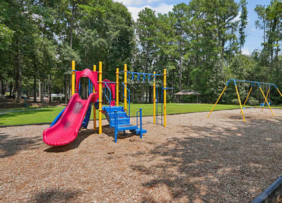 A playground with a red slide, blue bench, and yellow and blue play structures.