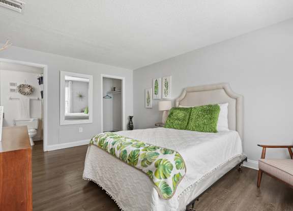 A bedroom with a bed, chair, and a mirror.