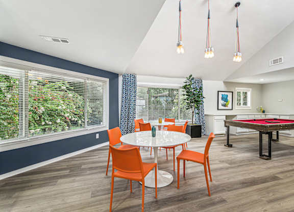 A dining room with a table set for four and a pool table.