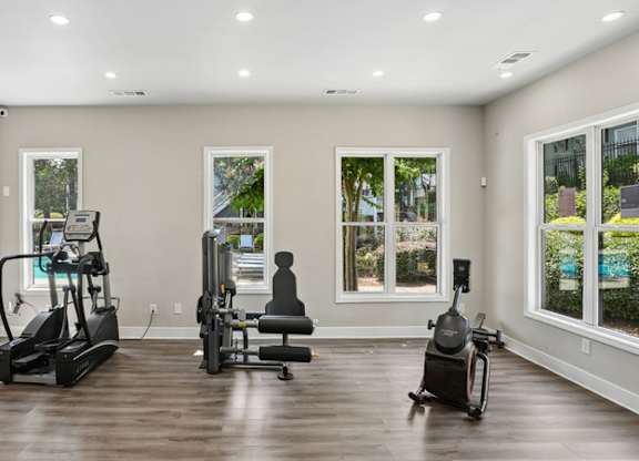 A spacious room with a treadmill, stationary bike, and rowing machine.