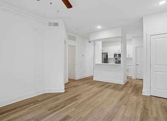 A spacious room with wooden flooring and white walls.