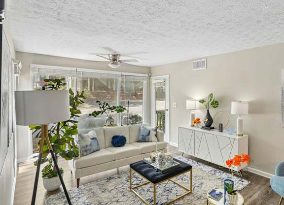 A living room with a white couch, a blue chair, and a painting on the wall.