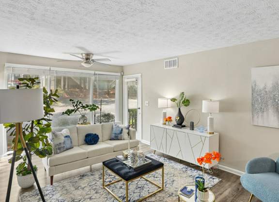 A living room with a white couch, a blue chair, and a painting on the wall.