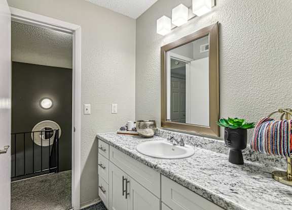 A bathroom with a sink, mirror, and a striped towel.