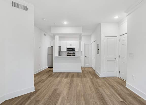 A kitchen with white cabinets and a wooden floor.