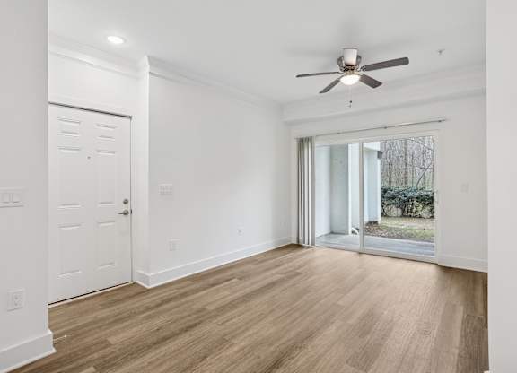 A room with a ceiling fan and sliding glass doors.