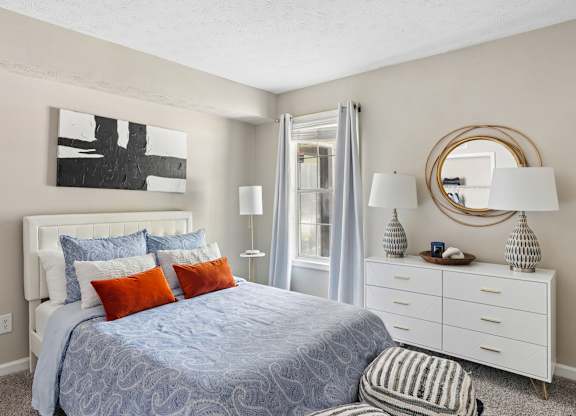 A bedroom with a bed, nightstand, and a painting on the wall.