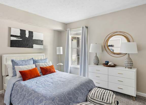 A bedroom with a bed, nightstand, and a mirror.