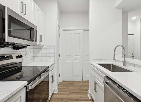 A kitchen with white cabinets and a black countertop.