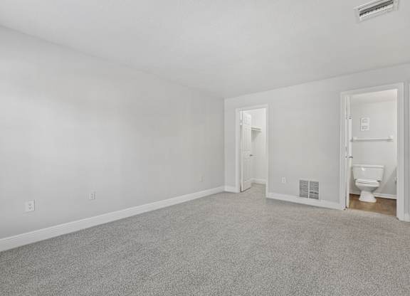 A white room with a carpeted floor and a toilet in the corner.