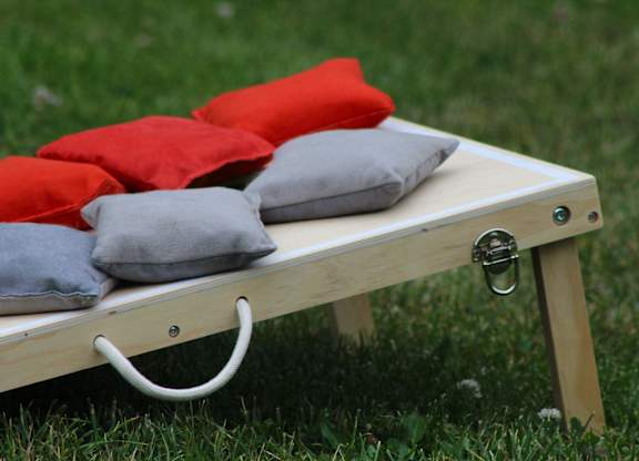 A wooden bench with red and grey pillows on it.