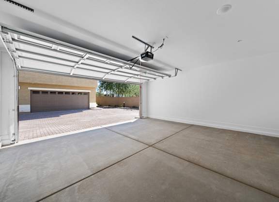 A spacious garage with a concrete floor and a ceiling fan.