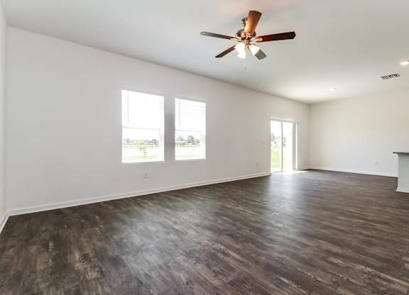 A room with a ceiling fan and wooden flooring.
