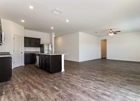 A spacious room with a kitchen area and a ceiling fan.