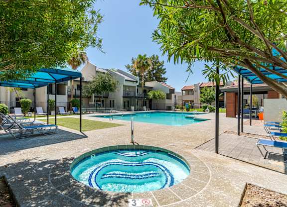 Swimming pool and spa at Sono Tempe Apartments in Tempe, Arizona surrounded by palm trees and community seating.
