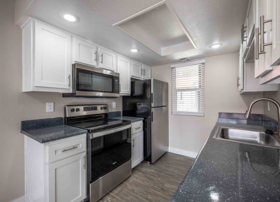 a kitchen with white cabinets and black counter tops