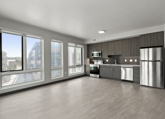 an empty room with a large window and a stainless steel refrigerator