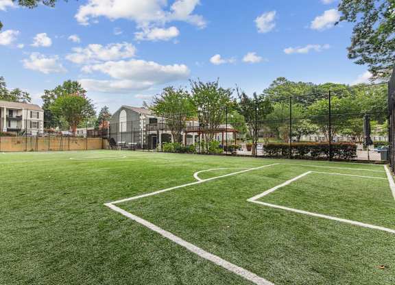 A tennis court surrounded by a fence and trees.