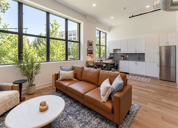 A brown leather couch with a white coffee table in front of it.