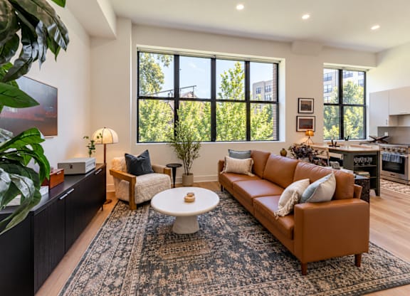 A living room with a brown couch and a large window.