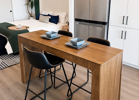 A kitchen with a table and chairs in front of a refrigerator.