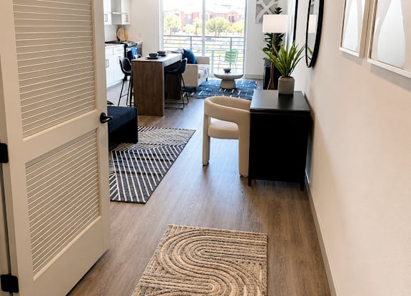 A hallway with a rug on the floor and a door on the left.