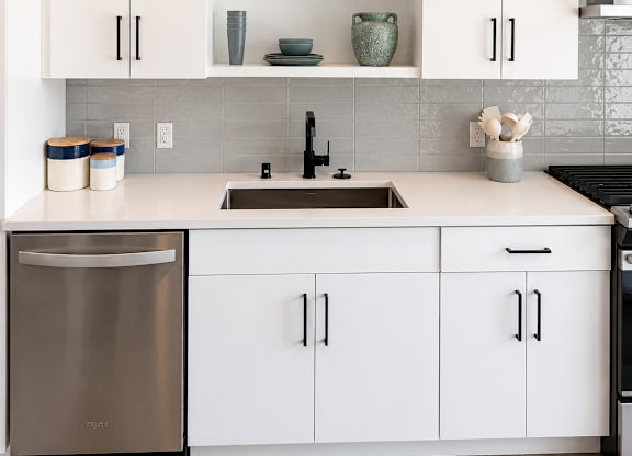 A modern kitchen with white cabinets and a stainless steel dishwasher.
