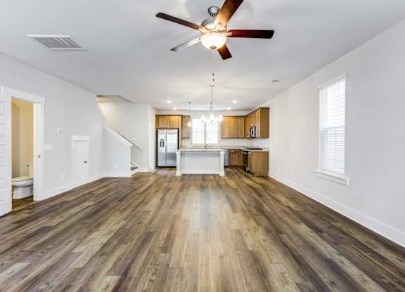 Park Circle Home Rentals - Sumner Village - Open-Floor Living Room With Vinyl Plank Flooring, Ceiling Fan, And Easy Access To A Toilet And Kitchen