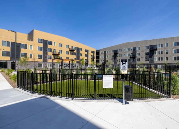 a fenced in grassy area in front of an apartment building
