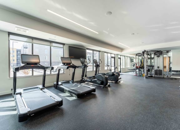 a gym with cardio equipment and windows in a building