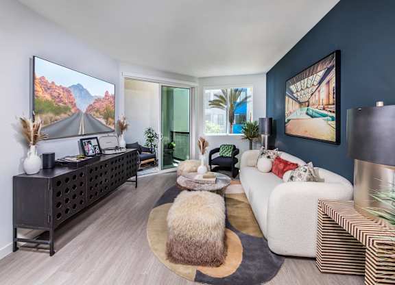 A modern living room with a large screen TV and a white sofa.