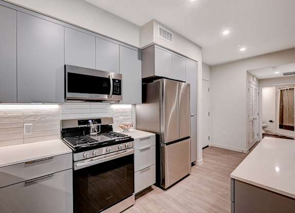 A modern kitchen with stainless steel appliances and white countertops.