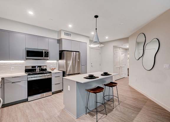 A modern kitchen with stainless steel appliances and a white island.