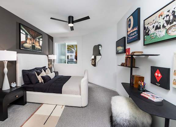 A bedroom with a bed, a table, and a ceiling fan.