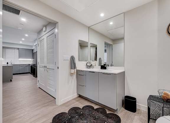 A bathroom with a vanity, mirror, and a rug.
