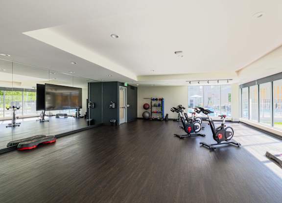 A gym with a row of stationary bikes and a row of exercise bikes.