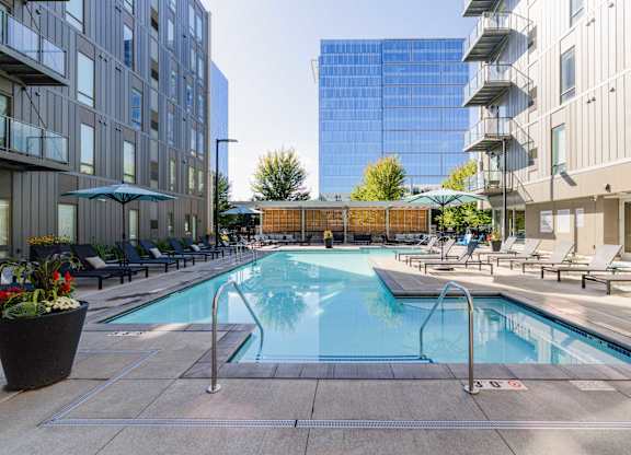 A pool surrounded by chairs and buildings.